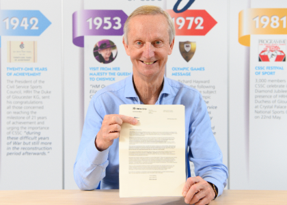 Hedley Featherstone MBE sat displaying his letter from HRH