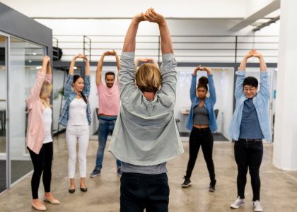 A group of office workers with their hands above their heads stretching