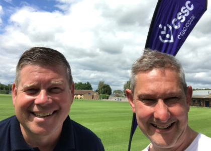 dave and neville stood outside on a field with a cssc sign behind them