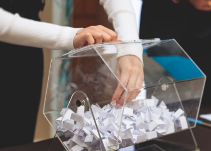 A woman selecting a prize ticket from a clear barrel