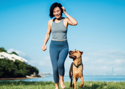 A woman walking her dog with a lake and mountain in the background